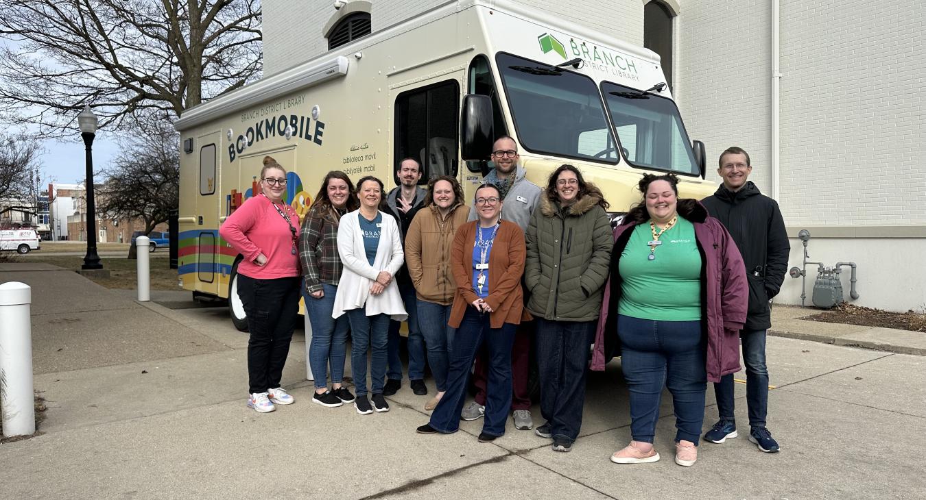 The BDL-Coldwater team stands with the bookmobile for a photo.